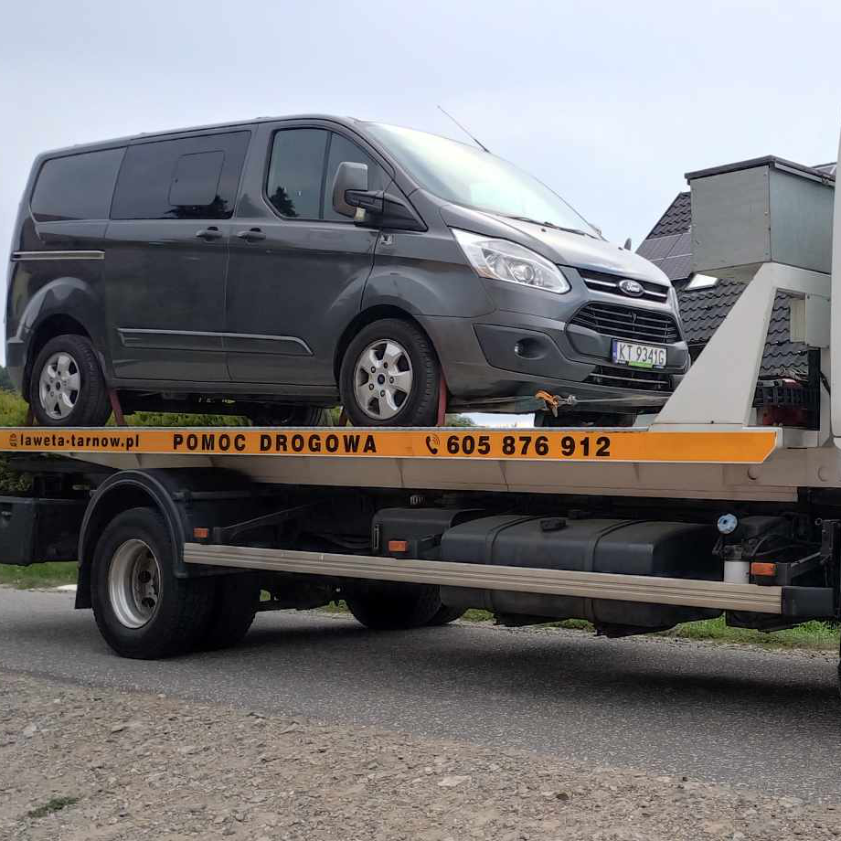 Transport busa firmowego lawetą w Tarnowie – pojazd typu L2H2 na platformie